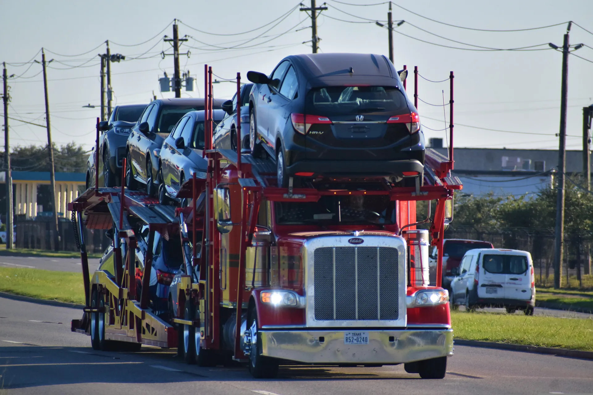 A vehicle being loaded onto an open auto transport trailer.