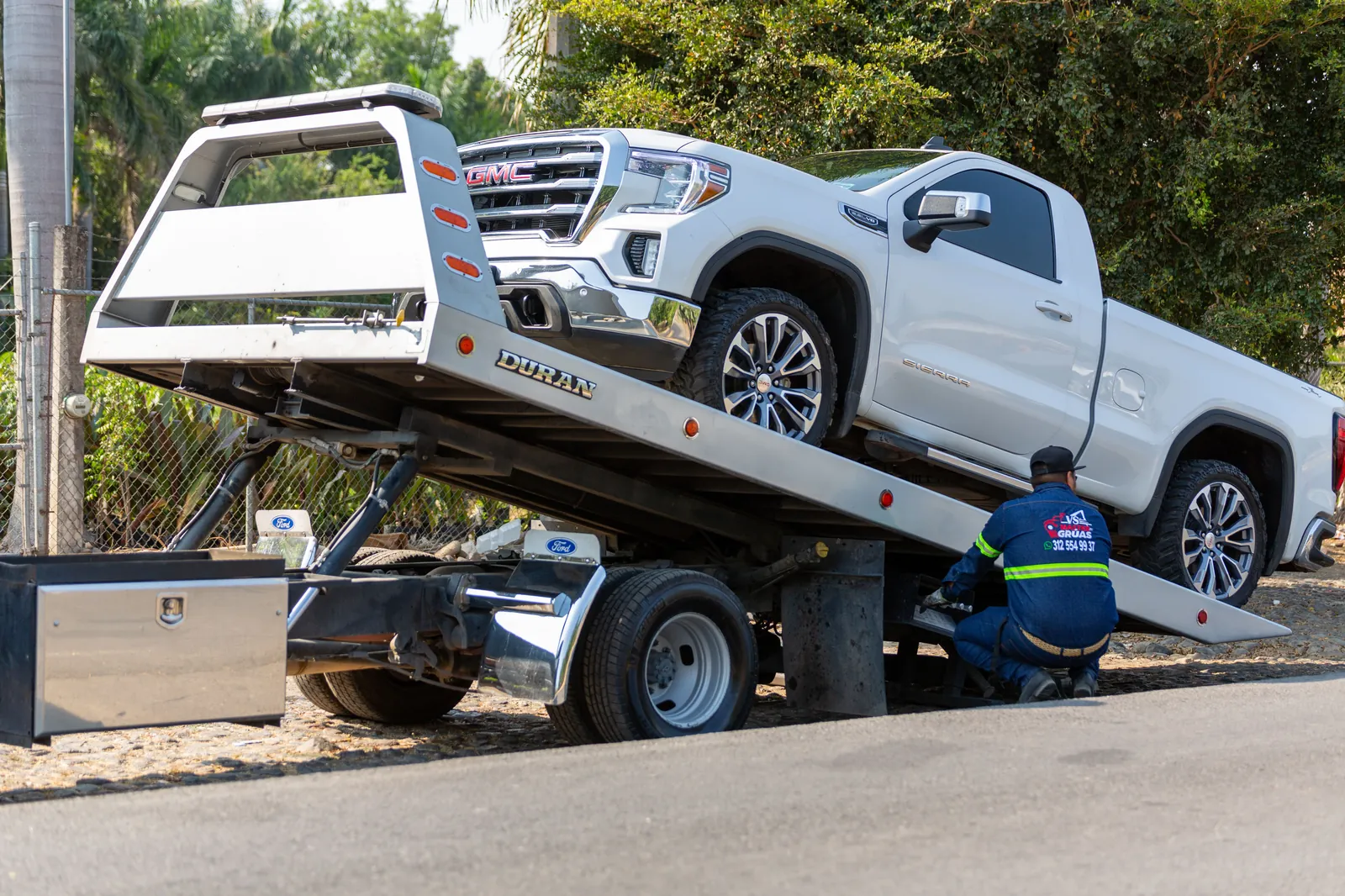 Car carrier delivering a sedan to a home in a suburban neighborhood.
